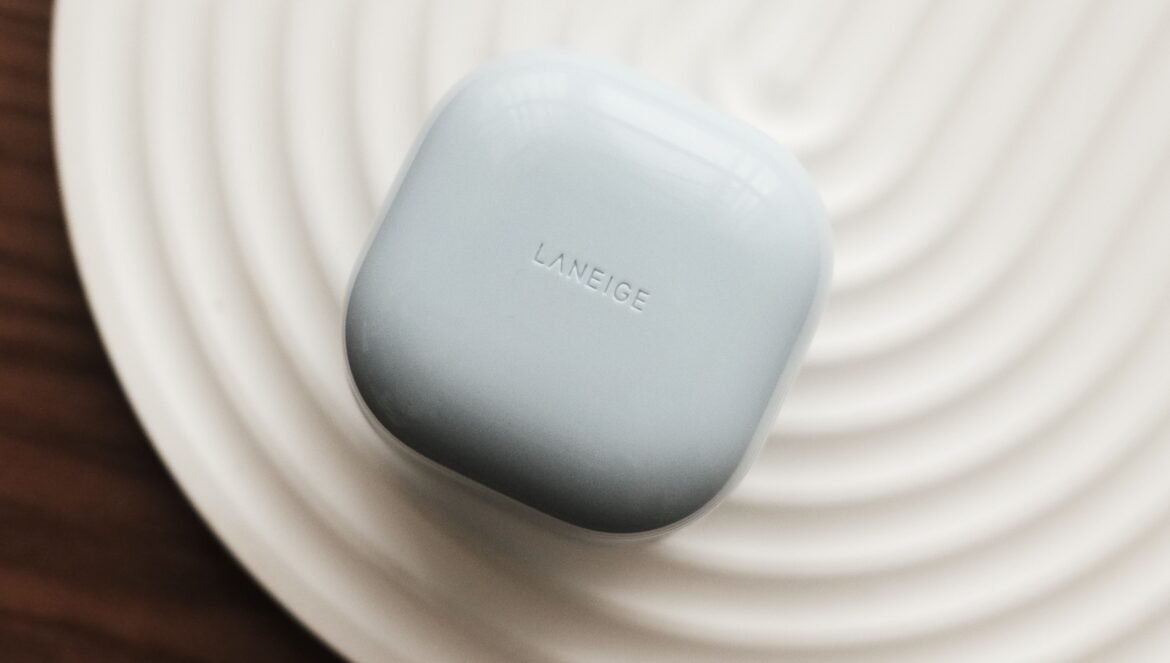 A top-down view of a light blue Laneige skincare jar resting on a white, circularly ribbed tray over a dark wooden surface.