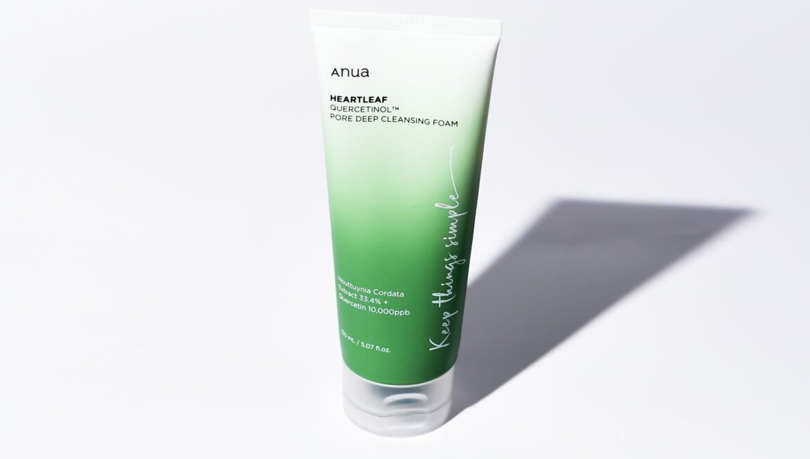 A tube of Anua Heartleaf Quercetinol Pore Deep Cleansing Foam resting on a white background with a sharp shadow. The packaging features a sleek white-to-green gradient.