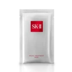 A photo of an individual SK-II Facial Treatment Mask packet, which is made of a matte silver metallic foil. In the top-center, there is a red square logo with "SK-II" in a white serif font. At the bottom-center of the packet, the text "FACIAL TREATMENT MASK" is printed in a thin, dark grey or brown sans-serif font. The packet is isolated against a clean white background with a soft reflection directly beneath it.