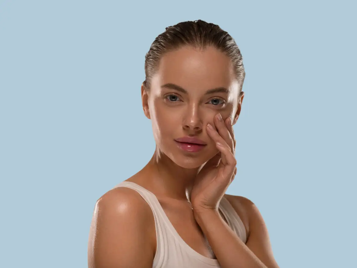 Model with dewy, glowing skin touching her cheek, illustrating the glass skin look linked to PDRN skincare