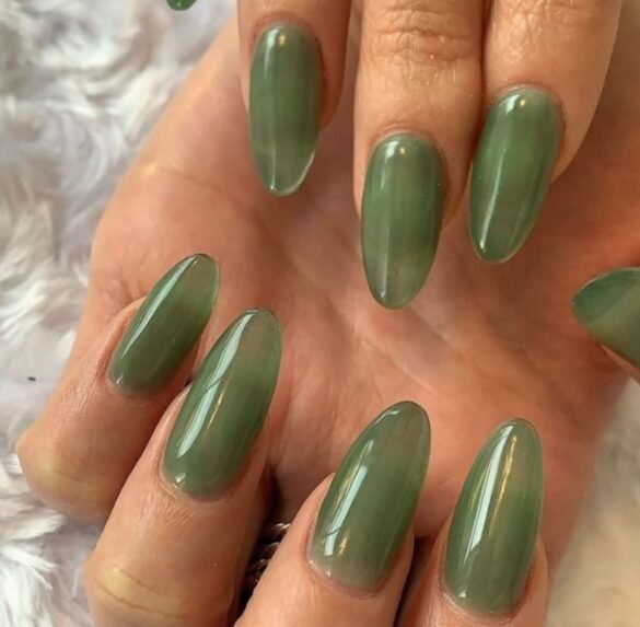 Close-up of a hand with long, almond-shaped nails painted glossy sage green.